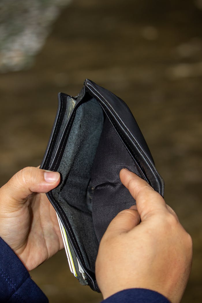 A close-up image of an empty leather wallet held by two hands, symbolizing financial challenges.